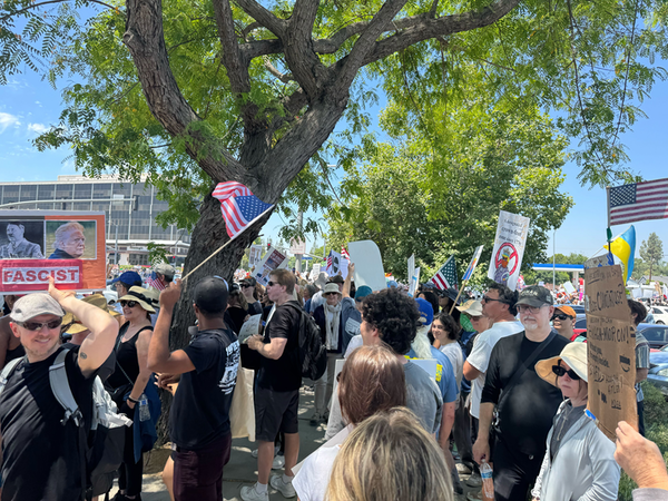 A photo of lots of people holding signs and wearing shirts opposing the Trump Administration.