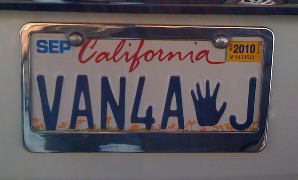 A close-up photo of a California license plate that says "VAN4A✋J".